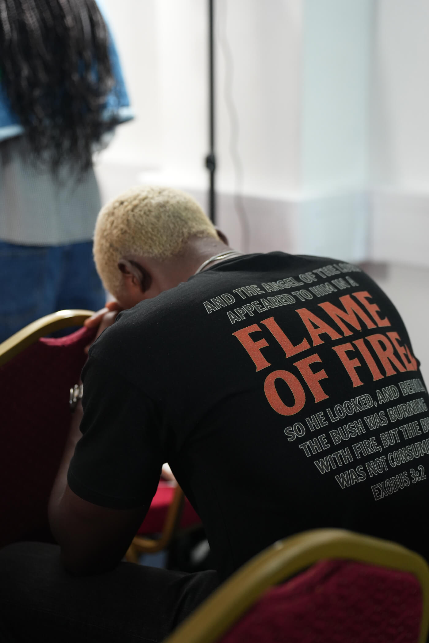 An attendee bowed in prayer, wearing a black Flame of Fire Exodus 3:2 T-shirt